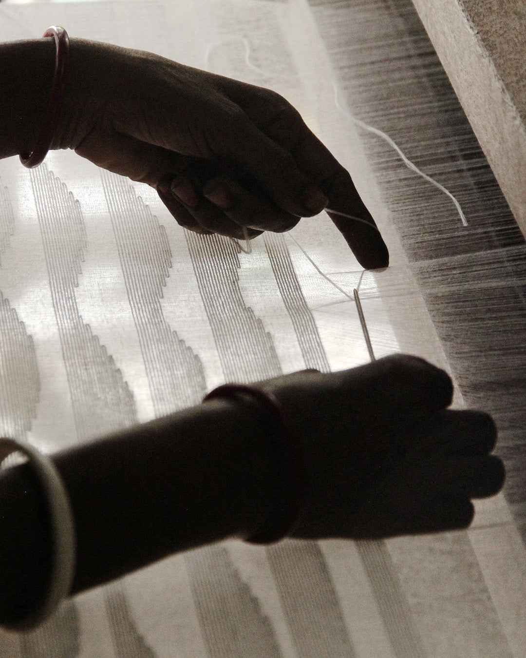 The hands of a Varana craftsman hand-weaving sustainable fabric