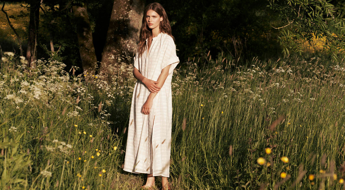 Woman standing in a field wearing a sustainably-made dress